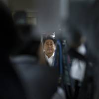 Center of the storm: Prime Minister Shinzo Abe is seen through television cameras as he arrives at a conference room in the party’s headquarters after the Upper House election. A dark age dawns for politics in Japan