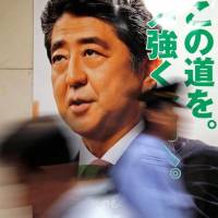 A revisionist path: Men walk past a poster for the July 10 Upper House election with the image of Prime Minister Shinzo Abe, leader of Japan’s ruling Liberal Democratic Party, at the LDP headquarters in Tokyo. The slogan on the poster reads: “Forward with strength this path.” How rights and liberties may be downsized under the LDP