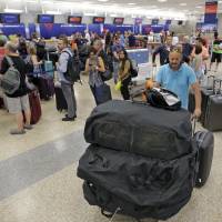 People push their bags as others stand in line after flights resumed Monday in Salt Lake City, following a computer outage. Delta Air Lines delayed or scrubbed hundreds of flights Monday after its computer systems crashed, stranding thousands of people on a busy travel day. Delta gets flights aloft after computer crash snarls global operations