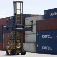 A forklift operates near stacked shipping containers at a port in the city of Shizuoka on June 27. Japan posted its largest current account surplus for a half-year period from January to June since the second half of 2007. At ¥10.63 trillion, January-June current account surplus largest since 2007