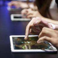 People play video games on tablet computers during the E3 Electronic Entertainment Expo in Los Angeles in June. Tablet makers in Japan aiming for corporate sales amid weak consumer demand