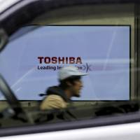 A Toshiba Corp. logo is seen through a car window in Tokyo. The company has been undergoing restructuring. Toshiba returns to black in April-June quarter with ¥79 billion net profit