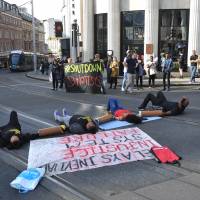 Activists lay on the road outside Nottingham Theatre Royal as they attempt to shut down part of the city center tram and bus network in Nottingham, England, on Aug. 5, 2016. Black Lives Matter protest blocks Heathrow access
