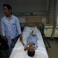 Wang Hongfa, 47, holds the hand of his 8-year-old son, Wang Lichang, at a hospital where he donated part of his liver to his ailing son in Hangzhou, in eastern China's Zhejiang province, in May 2013. Doctors divided on whether China still harvests organs from executed criminals