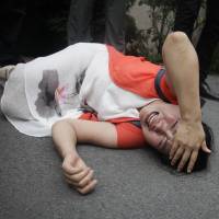 Fan Lili, the wife of imprisoned activist Gou Hongguo, lies on the ground in tears following an interaction with a plainclothes police officer outside the Tianjin No. 2 Intermediate People's Court in Tianjin, China, on Monday. Fearing secret trial, activists' friends protest China court