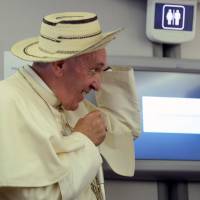 Pope Francis reacts while wearing a hat during a press conference on the plane after his visit to Krakow, Poland for the World Youth Days, on Sunday. Pope wants Aussie justice to play out before remarking on sex abuse claims against Cardinal Pell
