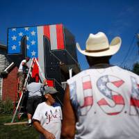 New York artist Scott LoBaido (on ladder) works on a Patriotic Lawn T in support of 2016 Republican presidential nominee Donald Trump in the area of Castleton Corners on Staten Island, New York, Tuesday. LoBaido's 12-foot-high T was destroyed by fire set by an unidentified arsonist on Sunday. Lobaido created a brand new statue that stands in the yard belonging to Trump supporter Sam Pirozzolo. Secret Service 'aware' after Trump quips gun rights advocates could stop Clinton