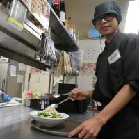 A Vietnamese (right) prepares to deliver a dish made by a Nepalese chef at Japanese pub Amataro in Nagoya. Foreign part-timers proliferate in Chubu as scarce Japanese flee drunks at pubs