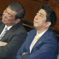 Then regional revitalization chief Shigeru Ishiba (left) and Prime Minister Shinzo Abe listen to a speech by an opposition party leader during a plenary session of the Lower House in July 2015. Ishiba's Cabinet exit may challenge Abe