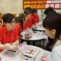 Cosmetics maker Shiseido Co. and glasses retailer Aigan Co. promote infrared-blocking products in Osaka on Aug. 3. Japan's latest fad: cosmetics, glasses that block infrared rays