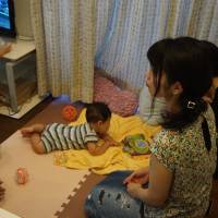 Two mothers, one of whom is a resident of shared house Codona HAUS in Tokyo's Suginami Ward, discuss their children during a community meal. The facility has four bedrooms set around a shared kitchen and living room. Shared homes offer respite for Japan's struggling single mothers