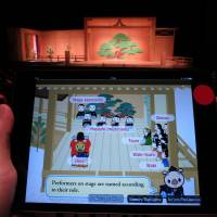 The screens display dialogue in Japanese or English, to help novice audiences follow the action. Noh players seek new audiences with live subtitles on tablets