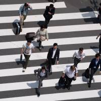 Pedestrians cross a road in Tokyo. Firms may soon be pressed to even out pay for regular and nonregular workers. Abe may try to address unequal pay