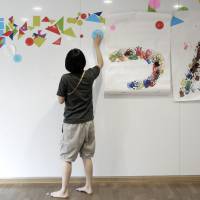 An employee decorates a wall at a nursery school, operated by Doronkokai, in Tokyo. Low pay haunts Tokyo's nurseries despite massive demand for places