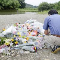 A man prays Sunday for 16-year-old Tsubasa Inoue on a riverbank in Higashimatsuyama, Saitama Prefecture, where his body was found partially buried last week. All teen suspects in Saitama slaying deny murderous intent