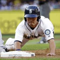 The Mariners' Norichika Aoki slides into first on a pick-off attempt during the third inning on Saturday in Seattle. Hernandez, Aoki help carry M's past Brewers