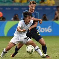 Shoya Nakajima vies for the ball with Sweden's Adam Lundqvist in their Group B match in Salvador, Brazil, on Wednesday. Japan eliminated despite victory over Sweden