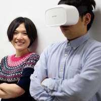 Yuka Kojima poses with a model wearing a Fove eye-tracking virtual reality headset in Tokyo on Sept. 20. Fove Inc. to debut VR goggles that track eyeball movements