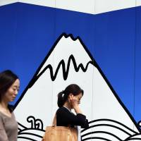 People pass a wall drawing depicting Mount Fuji while walking through Tokyo's Ginza shopping district on June 8. Japan's economy expanded at a better-than-estimated annualized pace of 0.7 percent in the April-June quarter. GDP revised upward to 0.7% for April-June quarter