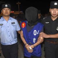 Chinese police escort an internet fraud suspect on Tuesday at Lukou International Airport in Nanjing, China, after deportation from Cambodia. Cambodia deports 63 Chinese, Taiwanese over alleged web scam