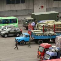 Cargo trucks and other vehicles wait at a border checkpoint to cross into North Korea in Dandong in northeastern China's Liaoning Province in March. China probes company accused of North Korea trade violations