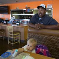 Adelanto City Council member Jermaine Wright talks to a reporter inside his Fat Boyz Grill restaurant on Sept. 6 about the development of marijuana cultivation. With him is his 19-month-old foster daughter, Nova. Californian city sees modern 'gold rush' in commercial cannabis cultivation