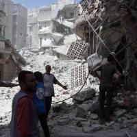 In this photo provided by the Syrian Civil Defense White Helmets, men stand amid rubble after airstrikes in the al-Mashhad neighborhood in the rebel-held part of eastern Aleppo, Syria, Wednesday. Syria tells Aleppo civilians to keep away from rebel sites as it moves to retake city