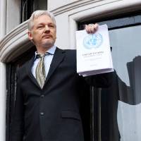 WikiLeaks founder Julian Assange addresses the media from the balcony of the Ecuadorian Embassy in London on Feb. 5, holding a report of the U.N.'s Working Group on Arbitrary Detention on his case. Swedish appeals court upholds detention order for Assange in rape case