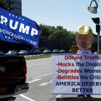 Protestor Tom Moran wears a paper mache head of Republican U.S. presidential nominee Donald Trump, as as a Trump supporter drives past, outside Hofstra University, the site of Monday's first presidential debate between Trump and Democratic presidential nominee Hillary Clinton, in Hempstead, New York, Sunday, Team Clinton hopes Trump's 'birther' slurs spur African-Americans to vote