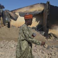 A man passes a burned-out building following an attack by Boko Haram in Bama, Nigeria, in February 2013. Biggest foe of Boko Haram refugees hunger, not violence