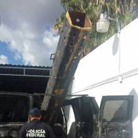 In this Saturday photo released by Mexico Federal Police, an officer stands next to a van outfitted with a 10-foot (3-meter) air cannon in Agua Prieta, Mexico, along the border with Douglas, Arizona. According to federal police, it was used to shoot projectiles into the U.S. and the van was reported stolen from the city of Hermosillo in the Mexican state of Sonora over the summer. Mexican cops find van with air cannon used to shoot pot into Arizona