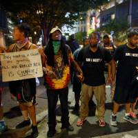 Marchers protest the police shooting of Keith Scott in Charlotte, North Carolina, on Sunday. As Charlotte Panthers play in tense city, protests outside remain peaceful
