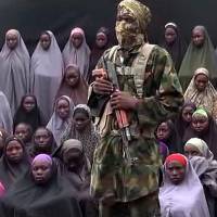 An Aug.14 video grab released on YouTube purportedly by Islamist group Boko Haram shows what is claimed to be one of the groups fighters at an undisclosed location standing in front of girls allegedly kidnapped from Chibok in April 2014. Chibok classes to resume two years after Boko Haram attack, abuctions