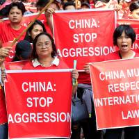 Filipino and Vietnamese activists display placards during a rally over their South China Sea disputes in front of a Chinese Consulate in Makati city, Metro Manila, on Aug. 6. ASEAN, China to adopt communications protocol to ease tensions in disputed South China Sea