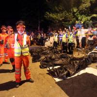 Rescuers stand in front of body bags after an explosion at a market in Davao City in the Philippines on Saturday. Duterte calls deadly market bombing act of terrorism, gives Filipino military extra powers