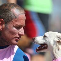 Ryan Rustan, 36, looks at his dog Sugar before it competes in the annual Surf City Surf Dog event on Tuesday in Huntington Beach, California. Man's best friend? It may be genetic