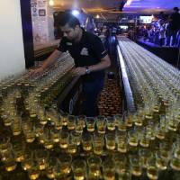 A crew member fixes new drinks after a misfire due to sound vibration before an attempt to make the world's longest domino drop shot on Monday at the Citymax hotel's Huddle Sports Bar & Grille in Dubai, United Arab Emirates. The biggest what? Dubai seeks glory in obscure world records