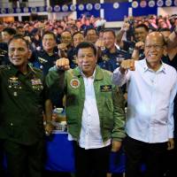 Philippine President Rodrigo Duterte (center) raises his fist with Philippine Air Force commanders during the 250th Presidential Airlift Wing anniversary at an air base in the Manila district of Pasay City on Tuesday. Duterte seeks arms from China, may end maritime patrols with U.S.