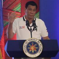 Philippine President Rodrigo Duterte raises a middle finger thrust out in an obscene gesture as he speaks before local government officials in Davao City, in the southern Philippines, on Sept. 20. Duterte wants alliances with Russia and China