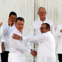 Colombian President Juan Manuel Santos (left) and Marxist rebel leader Rodrigo Londono (right), better known by the nom de guerre Timochenko, shake hands in Cartagena, Colombia, on Monday after signing an accord ending a half-century war that killed a quarter of a million people. Colombia, FARC sign historic peace deal ending half-century of armed conflict