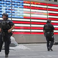 Heavily armed police officers stand guard in the Armed Forces recruitment center island in New York's Times Square on Sunday. Gov. Andrew Cuomo said 1,000 additional law enforcement officers were being deployed after the Saturday night blast in Chelsea. FBI questions car's occupants in NYC blast probe
