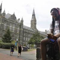 Deja Lindsey, 20, a junior at Georgetown University, talks on her cell phone in front of Healy Hall on campus Thursday in Washington. After renaming the Mulledy and McSherry buildings at Georgetown University temporarily to Freedom Hall and Remembrance Hall, Georgetown University will give preference in admissions to the descendants of slaves owned by the Maryland Jesuits as part of its effort to atone for profiting from the sale of enslaved people. Georgetown to atone for slavery legacy, give descendants priority admission