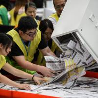 Electoral officials empty a ballot box for counting after voting stations closed for the Legislative Council election in Hong Kong early on Monday. New wave of anti-China activists set to win seats on Hong Kong's governing council