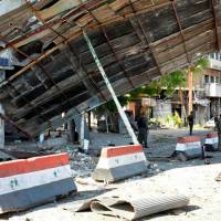 Syrian army soldiers stand at a site of an explosion in Bab Tadmor in Homs, Syria, in this handout picture provided by SANA on Monday. At least 48 killed in Islamic State bombings targeting Syria regime, Kurds