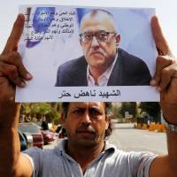 A relative of the Jordanian writer Nahed Hattar holds his photo during a sit-in in the town of al-Fuheis near Amman, Jordan, on Sunday. Gunman kills Jordanian writer charged for sharing anti-Islam cartoon