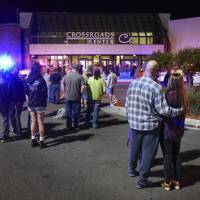 People stand near the entrance on the north side of Crossroads Center mall between Macy's and Target as officials investigate a reported multiple stabbing incident, Saturday in St. Cloud, Minnesota. FBI investigates Minnesota stabbings as possible terrorist act; Islamic State claims responsibility