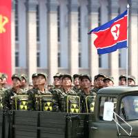 North Korean soldiers turn and look toward leader Kim Jong Un as they carry packs marked with the nuclear symbol during a parade marking the 60th anniversary of the Korean War armistice in Pyongyang in July 2013. Former U.S. officials, North Koreans hold Track 2 talks