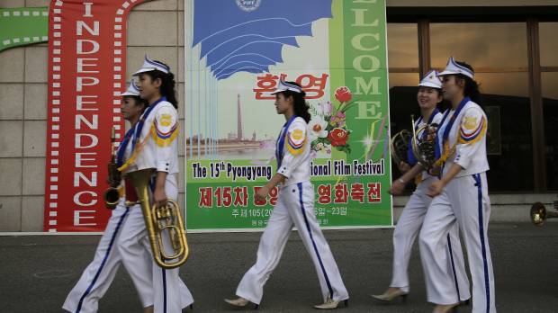 North Korean band members who performed at the Pyongyang International Film Festival walk past a sign at the venue where it was held Friday in the North Korean capital. Film about selfless woman who helps orphans takes top spot in North Korean festival