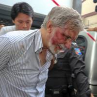 A foreign member of a suspected passport forgery gang is escorted by police officers after a raid in Bangkok, Thailand, on Friday. Foreign passport forgers charged with hiding body in Bangkok: police