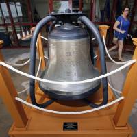 A woman passes the ship's bell from the USS Utah at the entrance to Tomich Hall on the grounds of the U.S. Naval War College in Newport, Rhode Island, Sept. 9. The hall is named after Peter Tomich, who died saving his shipmates aboard the Utah during the attack on Pearl Harbor. Pearl Harbor hero of 'forgotten ship' Utah reunited, in spirit, with its bell